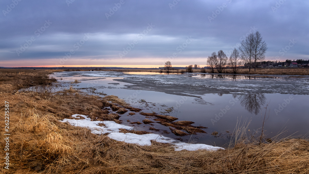 spring sunset panorama with trees on the river Bank and ice, Russia, Ural, April,