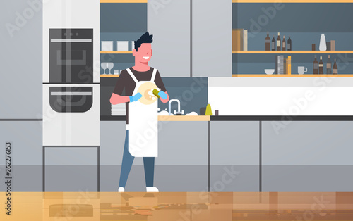 young man washing dishes guy wiping plates doing housework dishwashing concept modern kitchen interior flat horizontal full length