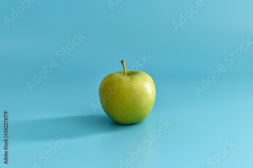 Juicy green apple on a blue pastel background. Minimal concept.