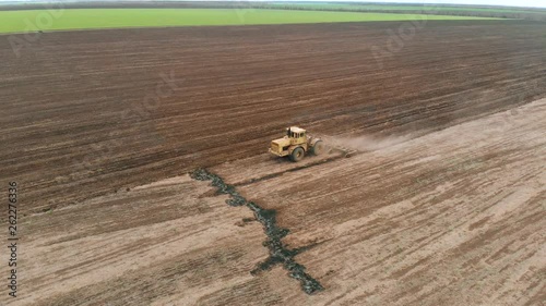 Aerial view on tractor with wide cultivator plowing soil after harvesting crops. Agronomic activities on farm photo