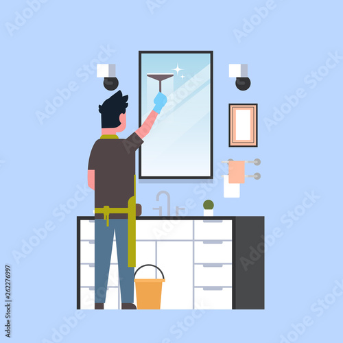 man in gloves and apron cleaning mirror with squeegee guy in bathroom doing housework concept rear view male character full length
