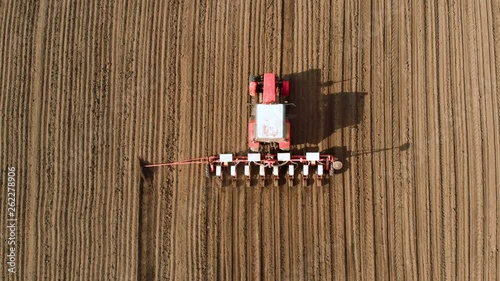 Top view on red tractor with row crop planter sowing sunflower seeds in open field. Agronomic activities on farm photo