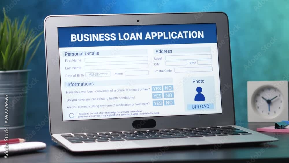 Laptop computer with a business loan application form on its display. Camera turning slowly around the desk.