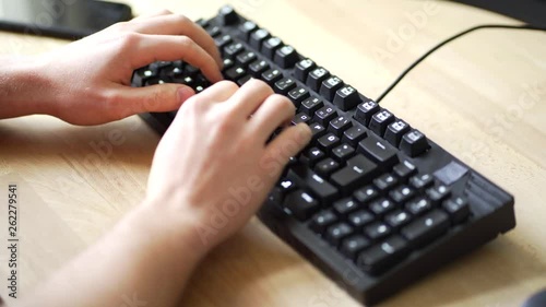 A male person is typing on a mechanical keyboard using the ten finger system