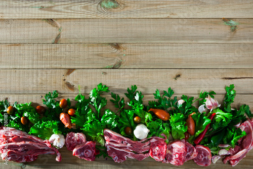 Raw lamb meat with vegetables on wooden background