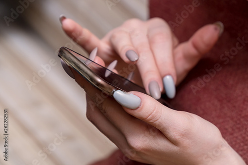 The girl touches her fingers to the phone screen. The girl has a manicure with false nails
