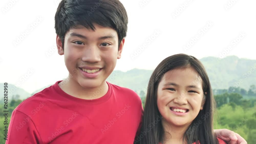 Portrait of happy asian boy and girl are looking at the camera with a beautiful smile in the middle of the natural view. Portrait of happy asian boy and girl are looking at the camera with a beautiful smile in the middle of the natural view.