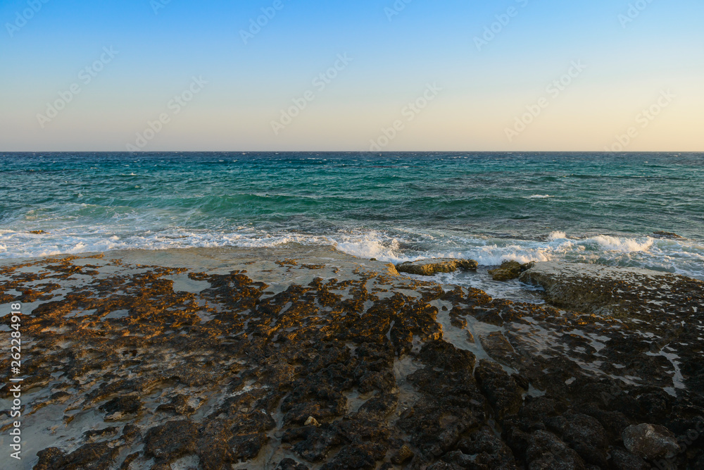 evening sea landscape with turquoise sea and rocky shore