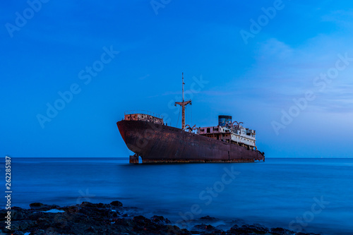 Spain, Lanzarote, Sunken rusty rotted wreck of temple hall ship at lava coast of arrecife in magical twilight
