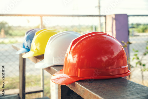 Safety helmet (hard hat) for engineer, safety and health officer or architect, place on old wooden floor. Multi color safety hat (helmet) in construction site. Safety equipment, construction concept photo