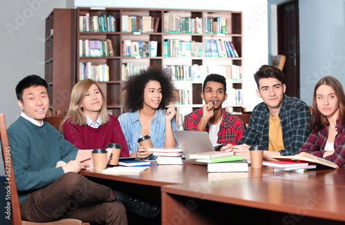 Group of students studying at table in library