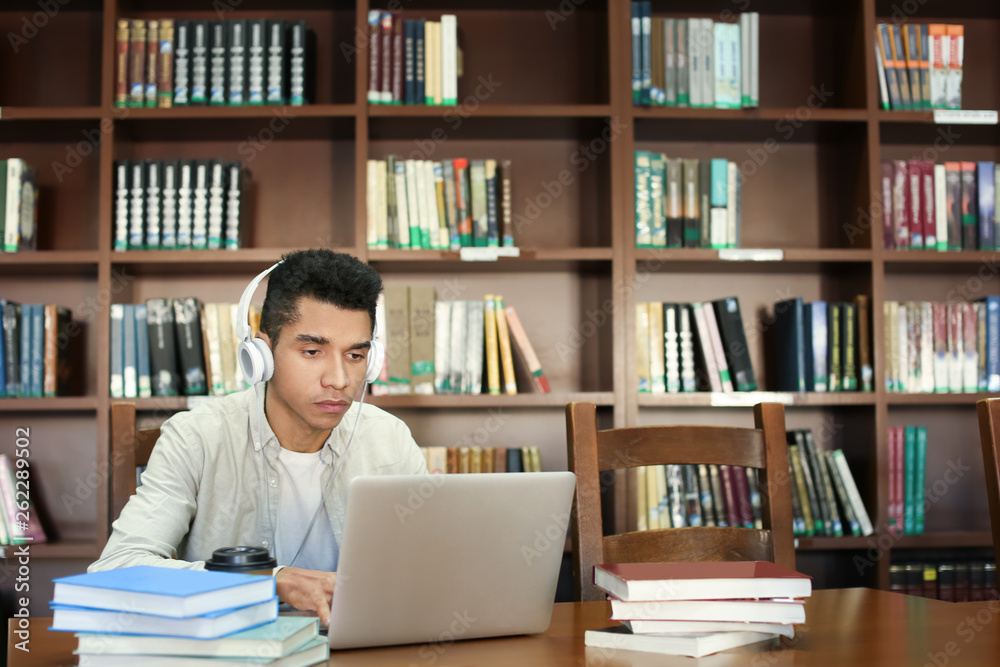 African American student with laptop studying in library African American student with laptop studying in library
