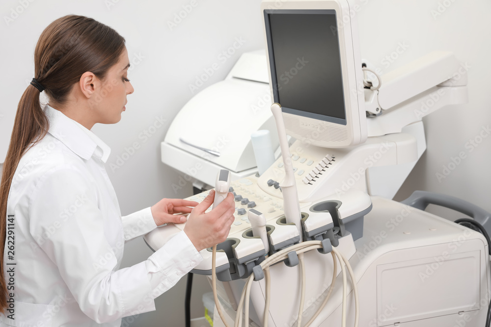 Professional sonographer using modern ultrasound machine in clinic Professional sonographer using modern ultrasound machine in clinic