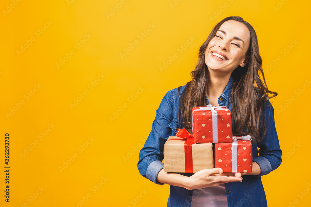 Young smiling model hold gift box. Woman isolated on yellow background. Young smiling model hold gift box. Woman isolated on yellow background.