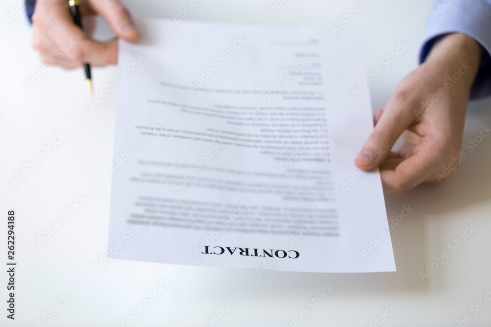 Businessman reading and checking terms and conditions at contract document Businessman reading and checking terms and conditions at contract document