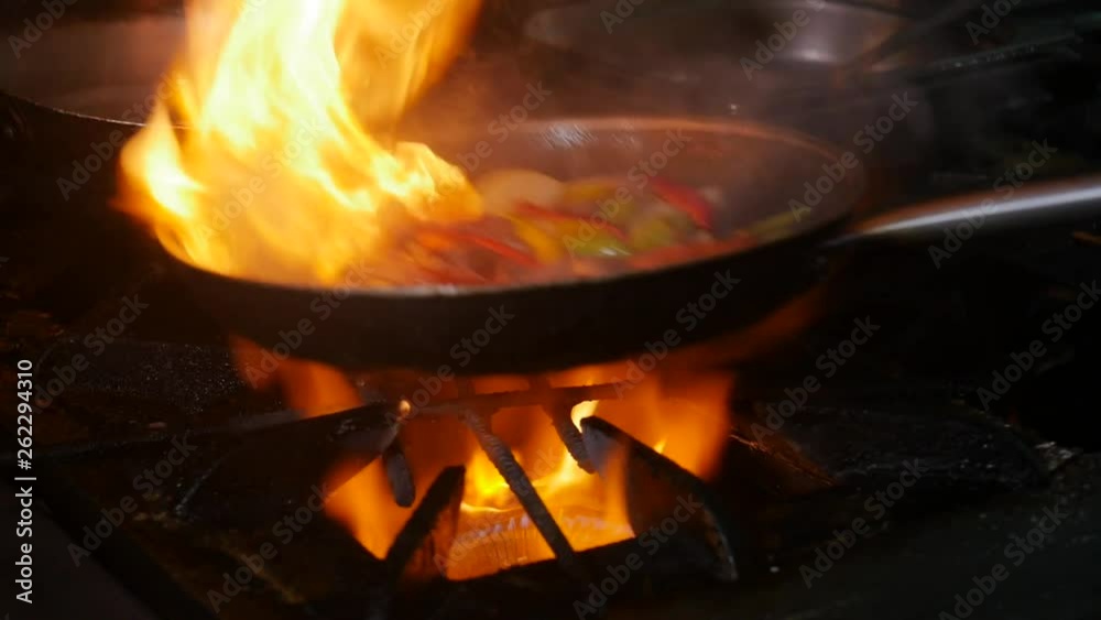 Professional chef and fire. Cooking vegetables and food over an open fire on a dark background