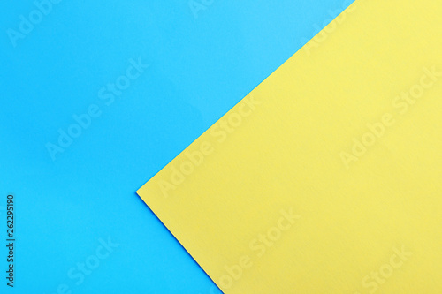 Blue and yellow paper sheets as colorful background, top view