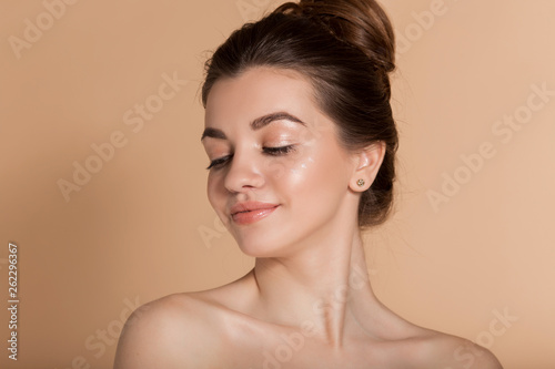 Beautiful face portrait of young woman with perfect skin with moisturizing face cream on a cheek. Skin care and health concept.