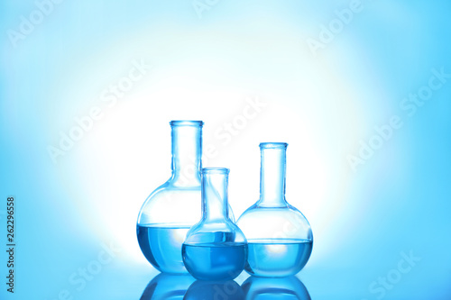Laboratory glassware with liquid on color background. Solution chemistry