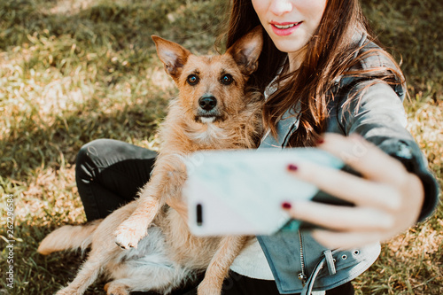 Valokuva .Pretty young woman playing with her dog in the park outdoors. Taking pictures t