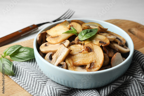 Delicious cooked mushrooms with basil served on table