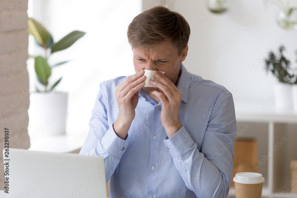 Sick man sitting at office and sneeze running nose. Sick man sitting at office and sneeze running nose.