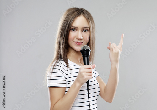 Beauty model girl singer with a microphone over light grey background