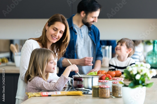 Beautiful cute family having fun while cooking together in the kitchen at home.