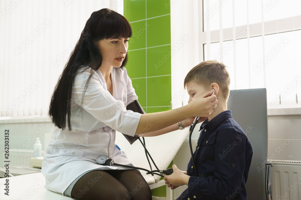 Mother - nurse teaches her little son to measure the pressure with a tonometer. Child at work with mom