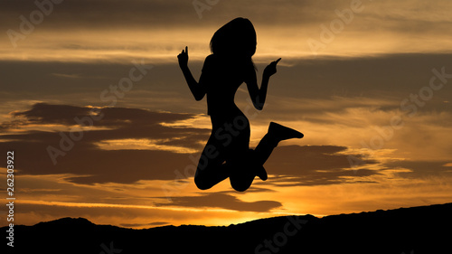 Shadow of woman jumping on sunset background