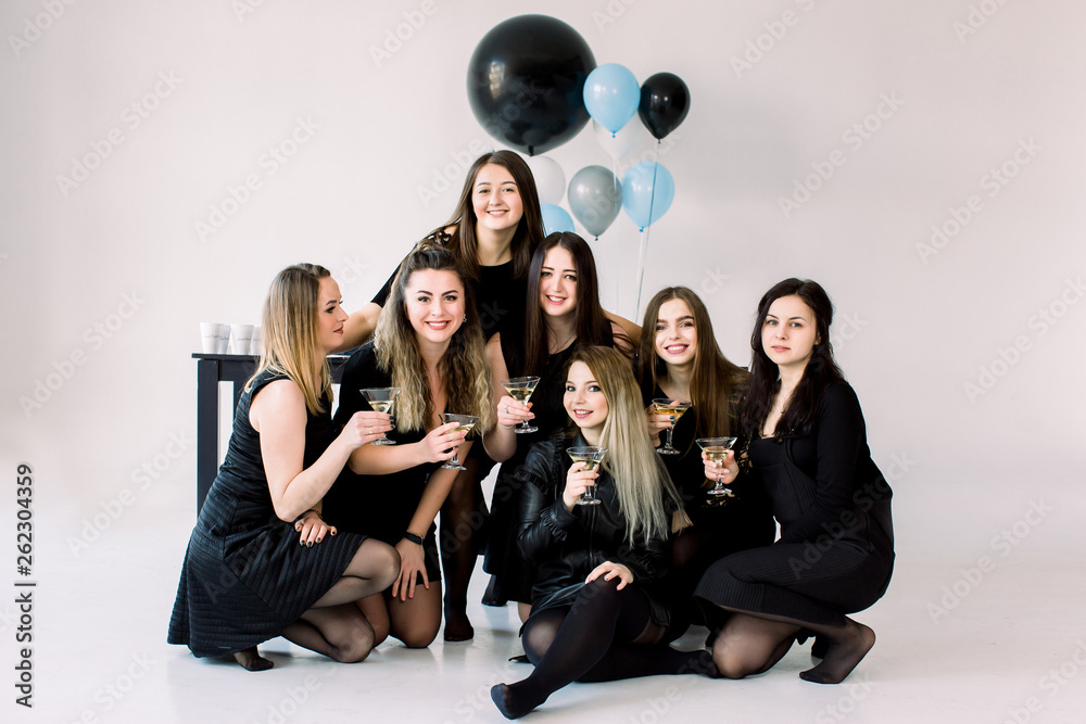 Brightfull expressions of happy emotions of seven amazing girls celebrating party on white background. Luxury black dresses, smiling, big balloons, stylish look. Birthday party concept