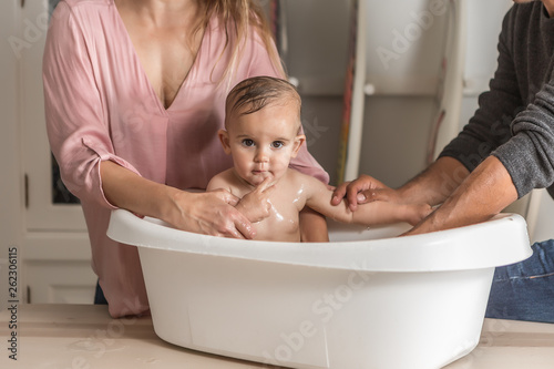 Foto Parents bathe the baby in the bathtub