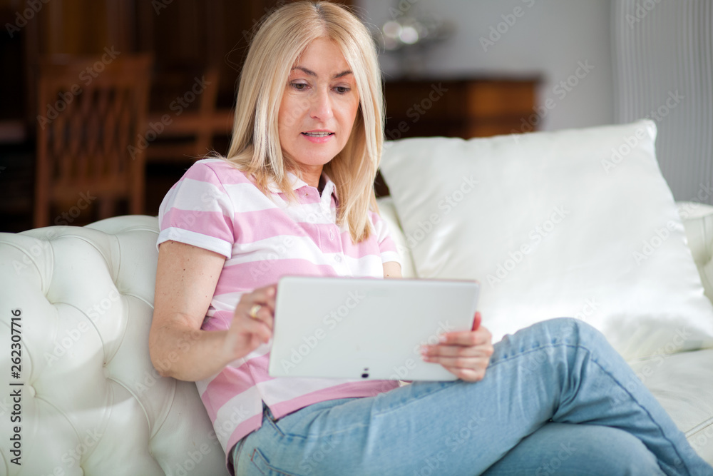 Beautiful mature woman using electronic tablet at home Beautiful mature woman using electronic tablet at home