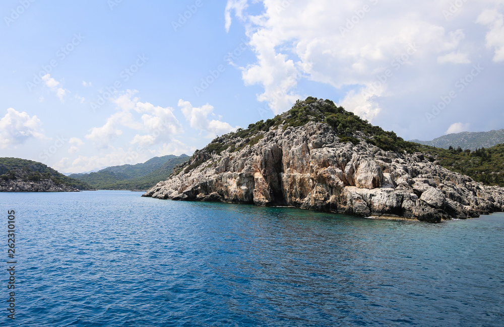 Fototapeta premium a view of the yacht on the blue waters and the various mountain scenery on the blue sky; travel pleasure in summer