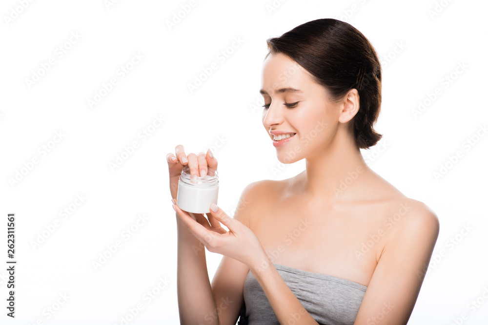 cheerful brunette woman looking at container with face cream and smiling isolated on white cheerful brunette woman looking at container with face cream and smiling isolated on white