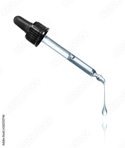 Thick drop is dripping down from cosmetic pipette on a white background photo