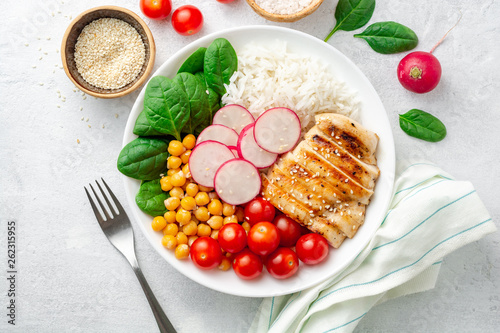 Billede på lærred Healthy buddha bowl with spinach, tomato, chickpea, rice, radish and grilled chicken on concrete background