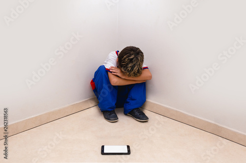 concept of cyber bulling. Child in school uniform crying in front of smartphone.