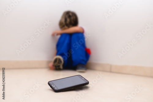 concept of cyber bulling. Child in school uniform crying in front of smartphone.