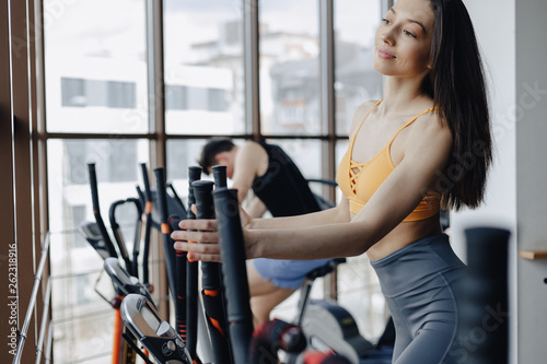 young attractive girl at gym on exercise bike, fitness and yoga