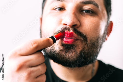 a man paints his lips with lipstick