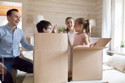 Family with children excited moving new house playing unpacking boxes