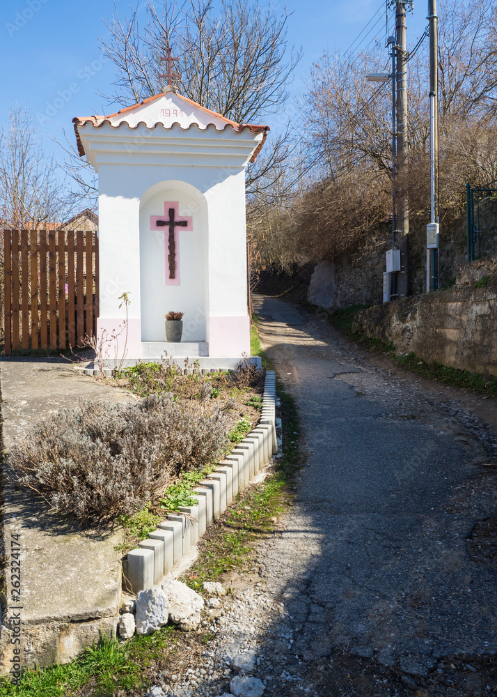 small white wayside shrine, road blessing or Gods torture with cross next village road curve in Srbsko, Czech republic