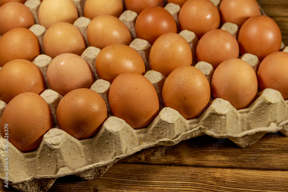 Raw chicken eggs in cardboard pack on wooden table Raw chicken eggs in cardboard pack on wooden table