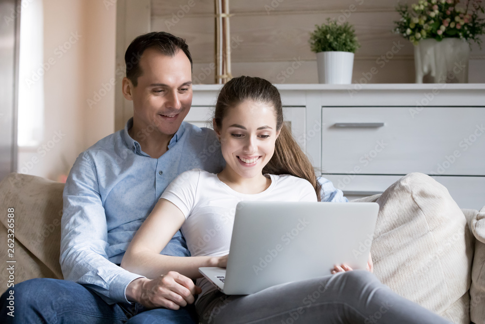 Happy smiling millennial couple watching video on computer at home Happy smiling millennial couple watching video on computer at home