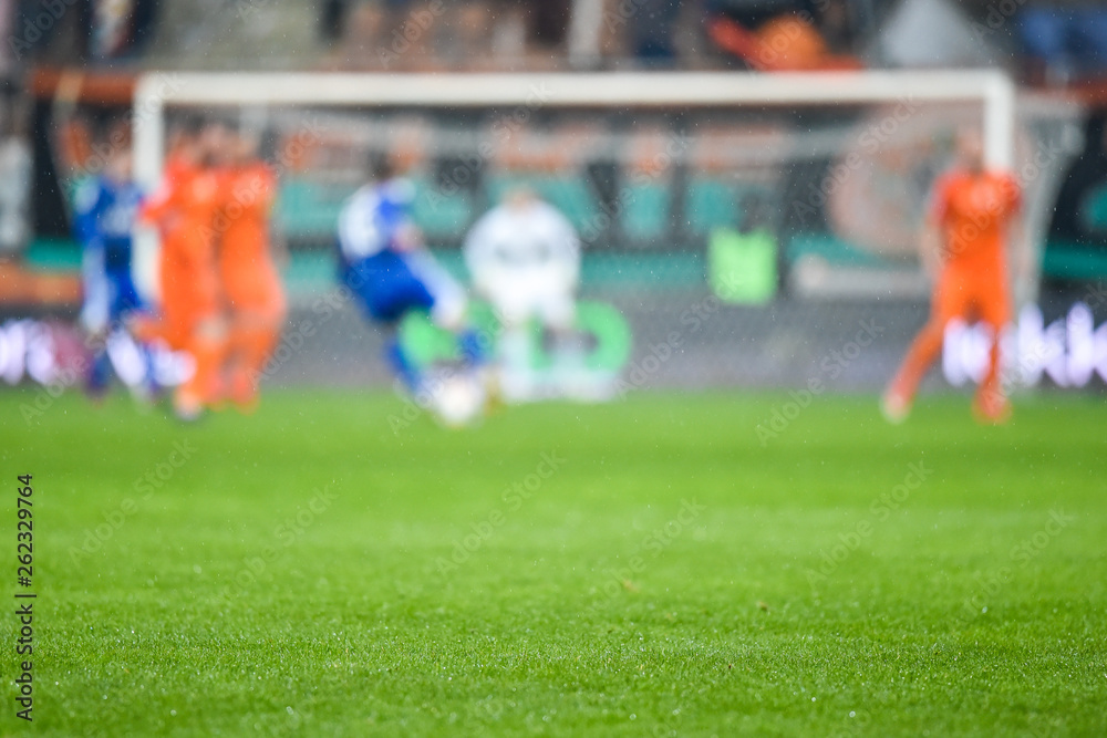 Fototapeta premium Grass on the football pitch with match in the background.