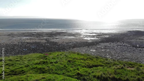 two friends sat on a bench at the beach on a cliff beautiful day 4k drone shot overhead