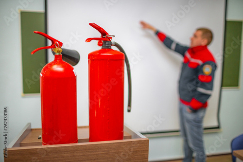 Uniformed fireman gives a lecture or instruction on fire safety. The instructor teaches the use of fire extinguisher