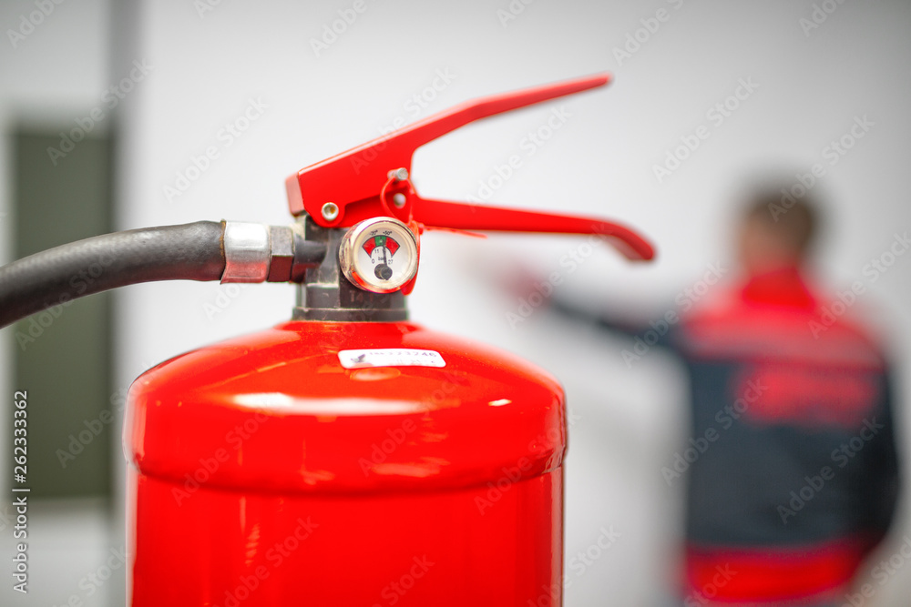 Uniformed fireman gives a lecture or instruction on fire safety. The instructor teaches the use of fire extinguisher
