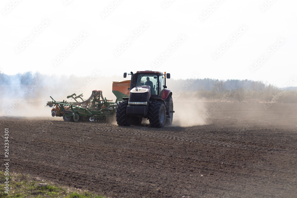 Fototapeta premium sowing time.tractor trailer rides on the field and sows grain